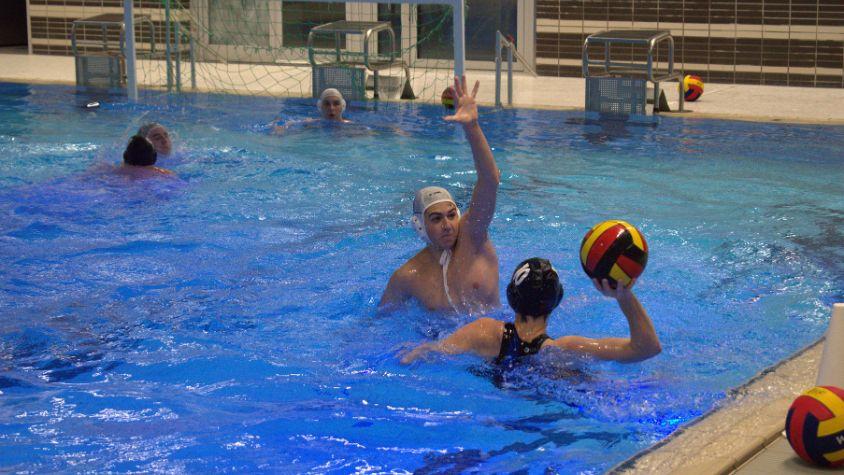 Eine Frau versucht einen Wasserball zu werfen, wird aber von dem Gegner geblockt.