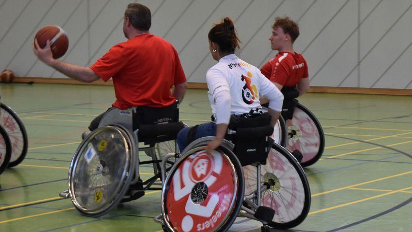 Drei Rollstuhlbasketballer*innen mitten im Spiel