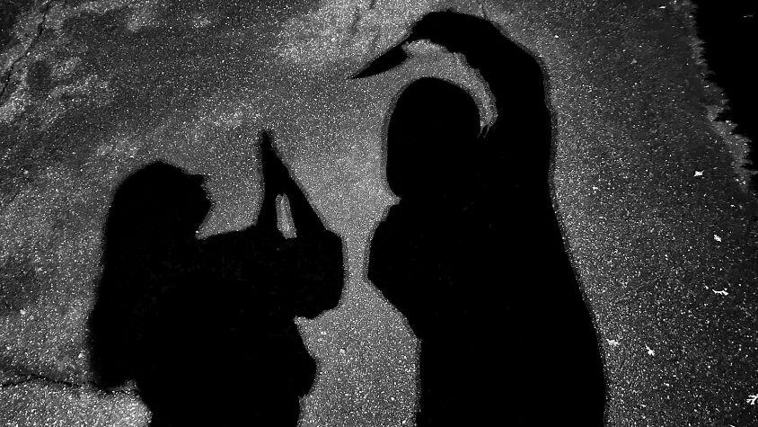 Schattenbild: Ein Mann bedroht eine Frau mit einem Messer.