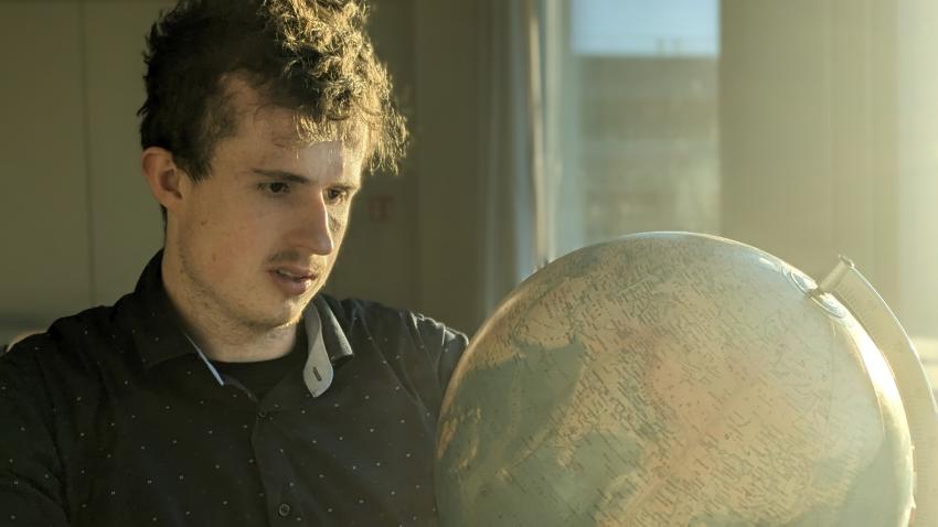 Ein junger Mann schaut auf einen Globus.