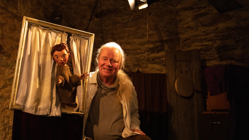 Der Puppenspieler Veit Utz Bross mit einer Handpuppe auf seiner Theaterbühne.