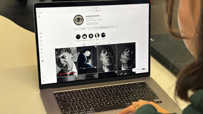 Zu sehen ist eine Frau von hinten, der Fokus liegt auf dem Laptop vor ihr. Auf dem Bildschirm ist der Instagram-Kanal "doublethinkdouble" zu sehen.