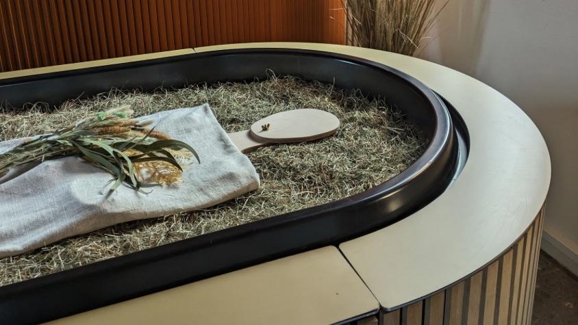 Eine Holzfigur liegt in einem sargähnlichen Behältnis, dem Kokon.