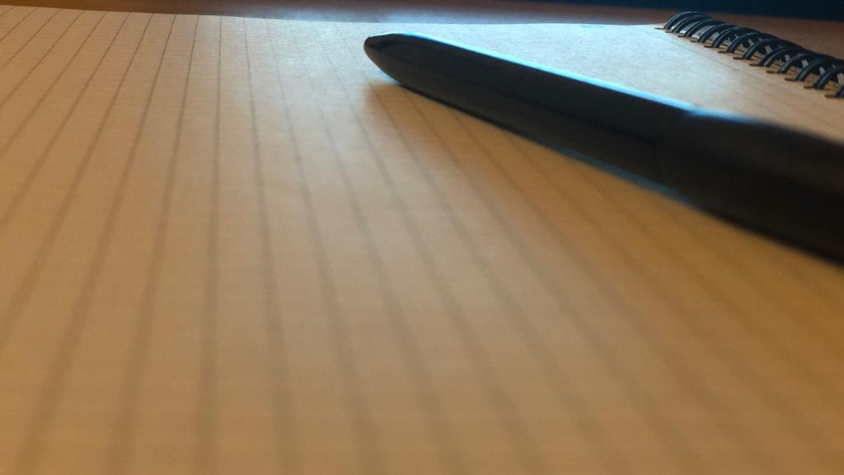 Ein schwarzer Kugelschreiber auf einem weißen Blatt Papier.