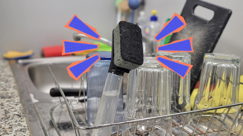 Eine Spülbürste steht in einem Abtropfbecken mit Abwasch. Rechts und links neben der Spülbürste sind gezeichnete Führungslinien.