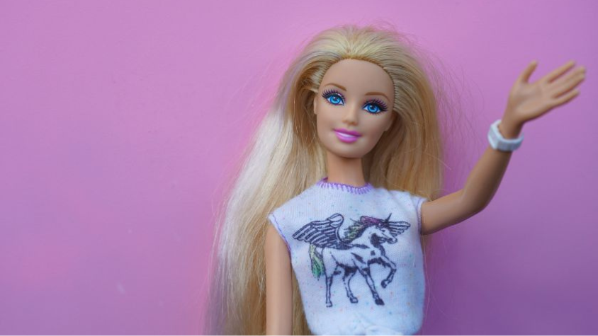 Eine blonde Barbie vor einem pinken Hintergrund.