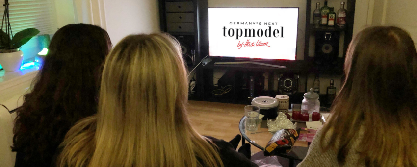 Drei junge Frauen sitzen im Wohnzimmer und schauen Germany's next Topmodel.