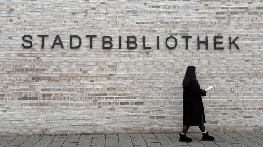 Mädchen läuft vor Bibliothek mit einem Buch