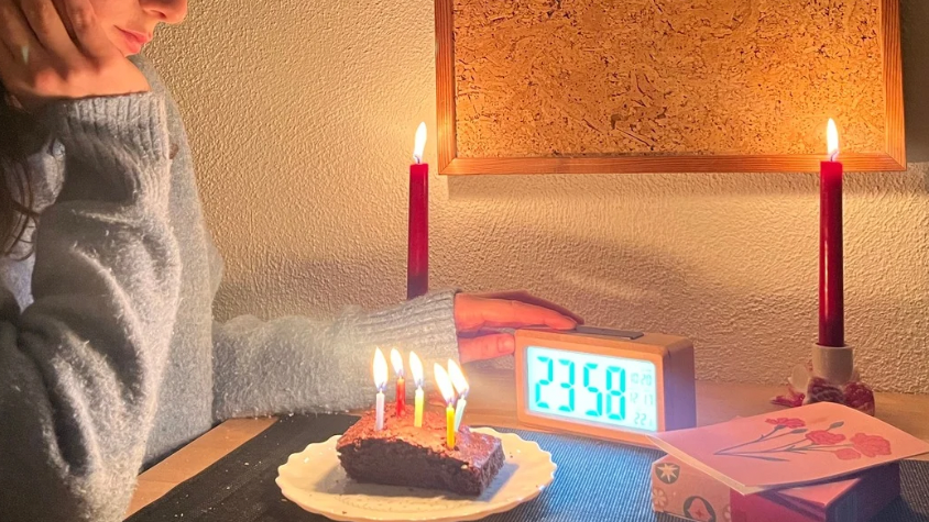 Jemand schaut auf einen Wecker mit 23:58 Uhr.