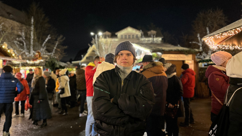 Ein junger Mann alleine auf dem Weihnachtsmarkt.