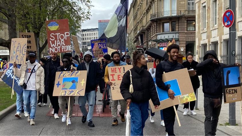 Menschengruppe läuft mit Demoplakaten auf der Straße