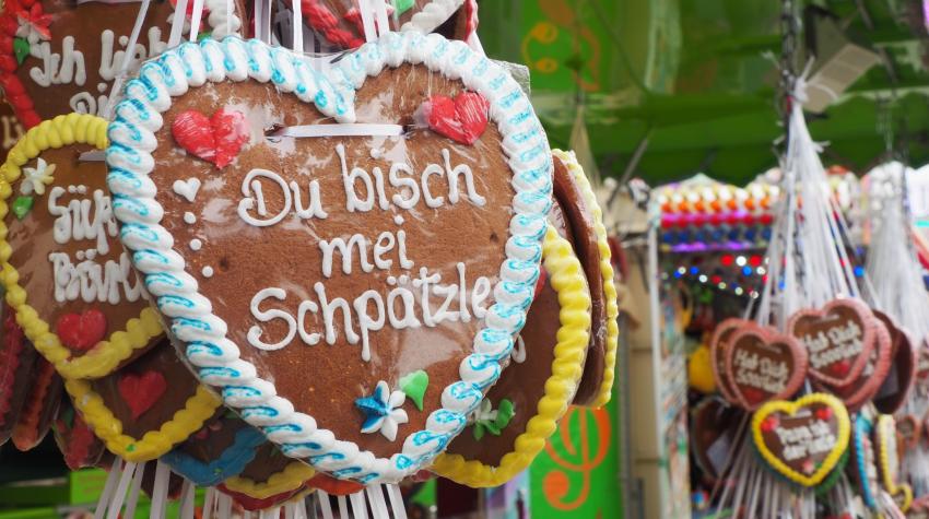 Ein Lebkuchenherz mit der Aufschrift "Du bisch mei Schpätzle" hängt an einem Stand auf dem Frühlingsfest, der Lebkuchenherzen verkauft.