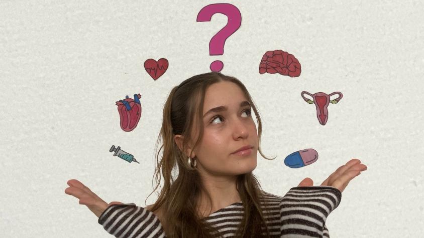 Frau steht vor weißer Wand, an der verschiedene Motive rund um weibliche Medizin kleben.