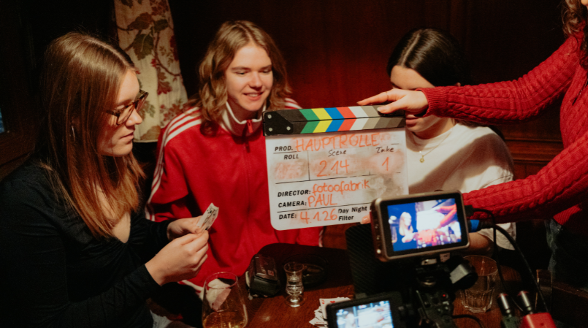 Musikvideo-Dreh für Felis Song, Dreh in einer alten Mainzer Kneipe. Feli sitzt in der Ecke, um sie herum wird Karten gespielt. Vor ihr wird die Klappe zugeschlagen – Die nächste Szene beginnt.