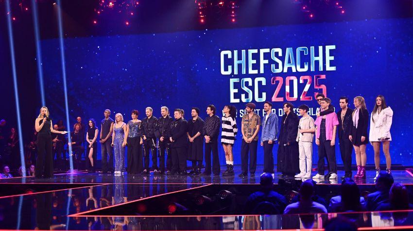 Die Teilnehmenden der zweiten Vorrunde stehen nebeneinander auf der Bühne. Links steht Barbara Schöneberger. Auf dem Bildschirm im Hintergrund steht "Chefsache ESC 2025".