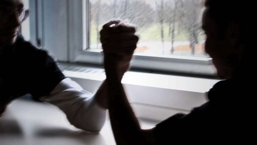 Zwei Männersilhouetten machen Armdrücken