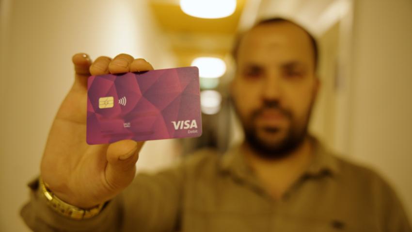 Geflüchteter Ammar hält seine Bezahlkarte in die Kamera