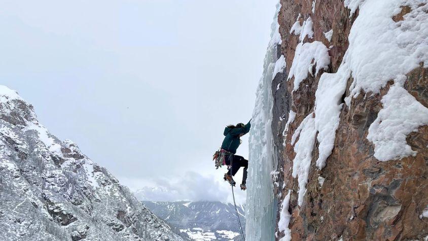 Sportlerin beim Eisklettern an einer vereisten Felswand.