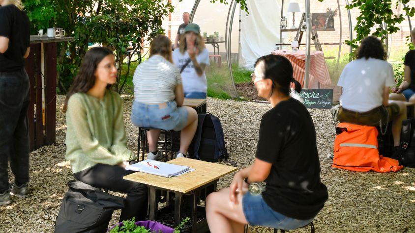 At an outdoor-event, people sit together in pairs of two and have conversations.