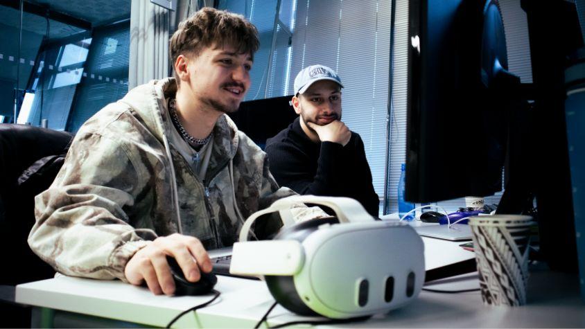 Zwei Männer sitzen mit einer VR-Brille vor einem PC