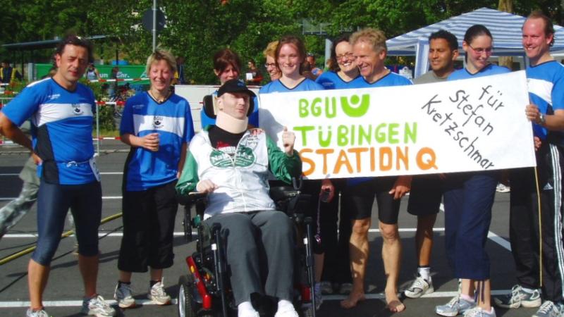 Die Ärzte und Pfleger nach der Teilnahme bei einem Triathlon zur Unterstützung von Stefan. Sie halten ein Plakat in der Hand mit der Aufschrift: „für Stefan Kretzschmar“.