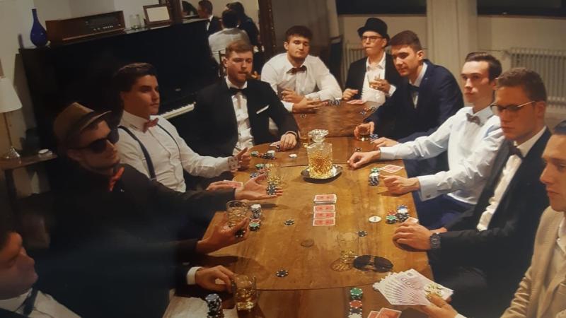 Marcel und seine WG-Mitbewohner posieren für ein weiteres humorvolles WG-Bild an einem Pokertisch.