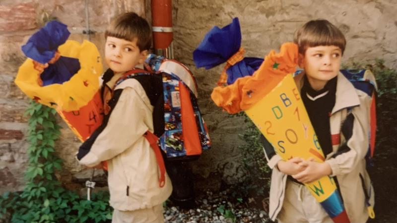 Henrik und sein Zwillingsbruder stehen bei ihrer Einschulung mit Schultüte nebeneinander.