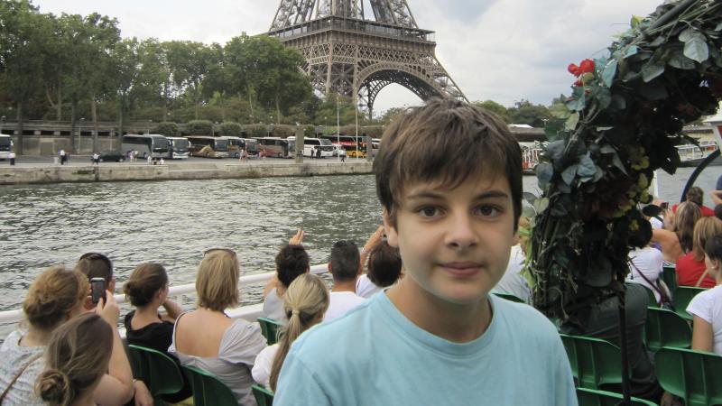 Henrik fährt mit einem Boot auf der Seine und im Hintergrund ist der Eiffelturm zu erkennen.
