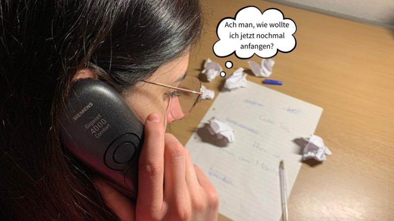 Frau hat den Hörer am Ohr, die Notizen liegen auf dem Tisch und bevor jemand abnimmt überlegt sie, wie sie anfangen wollte.  