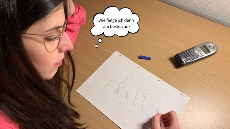 Frau sitzt vor einem Notizzettel und überlegt sich, wie sie das bevorstehende Telefonat beginnen soll. 