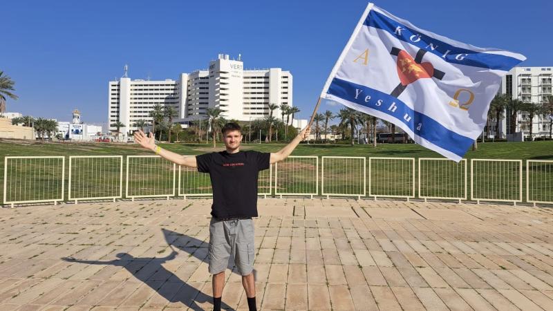 Marcel hält in Israel eine christliche Flagge hoch.