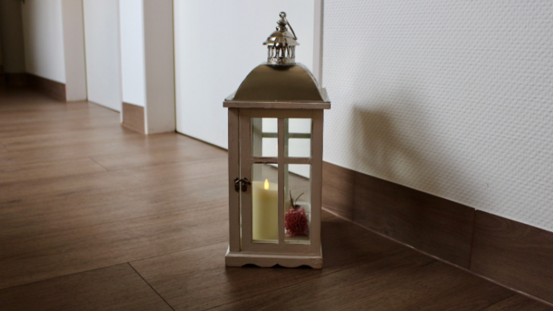 Eine Kerze steht vor einer Zimmertür. Diese Kerze steht für Gäst*innen, die gestorben sind.