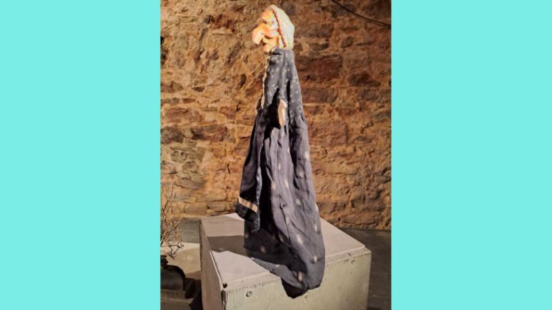 Figur einer Hexe mit langem, schwarzen Mantel.