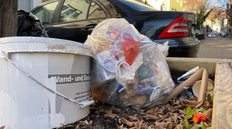 Ein Müllsack und Wandfarbe wurden in einem Blumenkasten um einen Baum herum abgeladen.