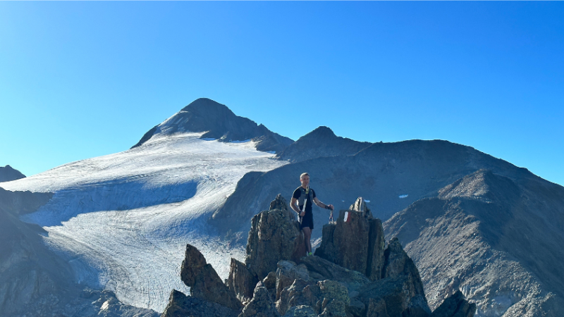 Mann steht auf einer Bergspitze