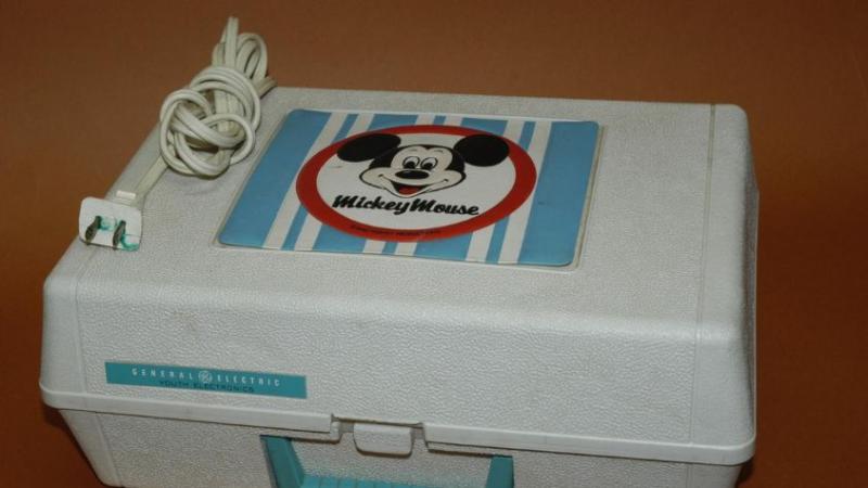 Ein tragbarer Koffer mit integriertem Plattenspieler für Kinder, mit einem „Micky Maus” Motiv ausgestattet.