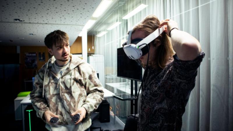 Ein Mann erklärt einem anderen Mann ein VR-Headset