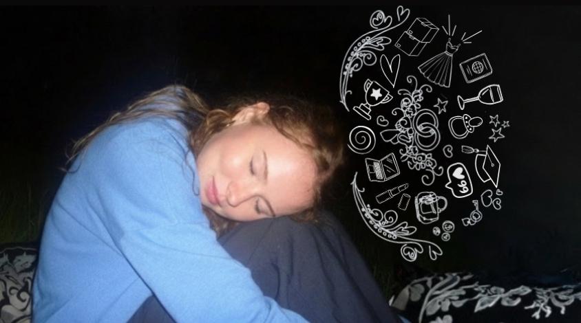 Frau sitzt im Dunkeln. Die beine sind an den Körper herangezogen und der Kopf ist auf den Knien abgelegt.