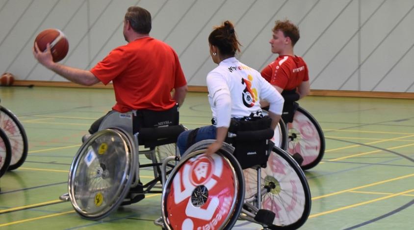 Drei Basketballsportler*innen mitten in einer Spielszene
