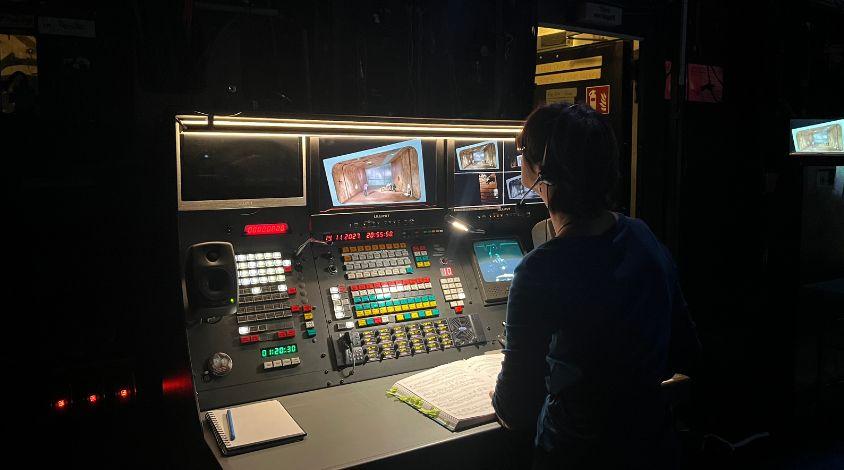 Inspizientin ist über Arbeitspult gebeugt.