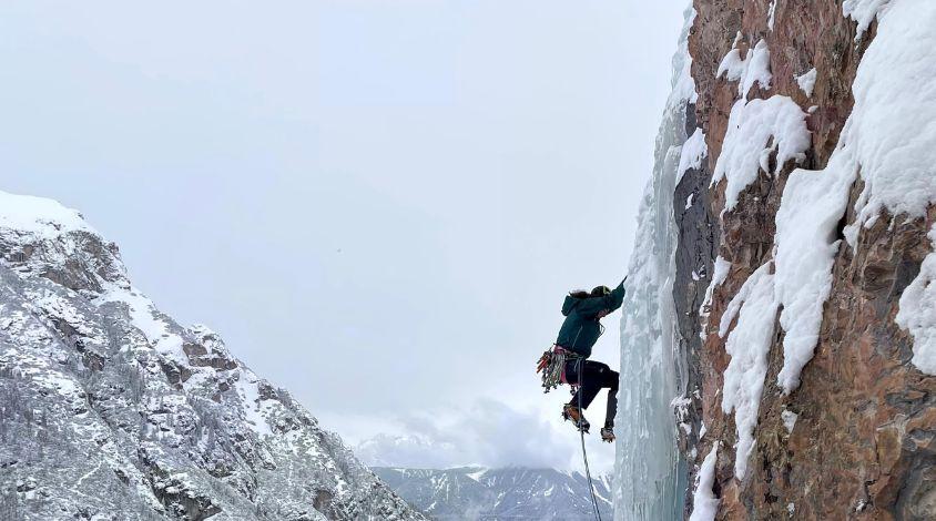 Sportlerin beim Eisklettern an einer vereisten Felswand.