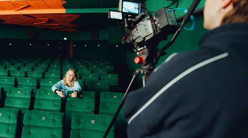 Feli sitzt alleine in einem leeren Kinosaal, schaut in die Ferne. Dreh ihres Musikvideos zur Single „Hauptrolle“, Kamera auf sie gerichtet